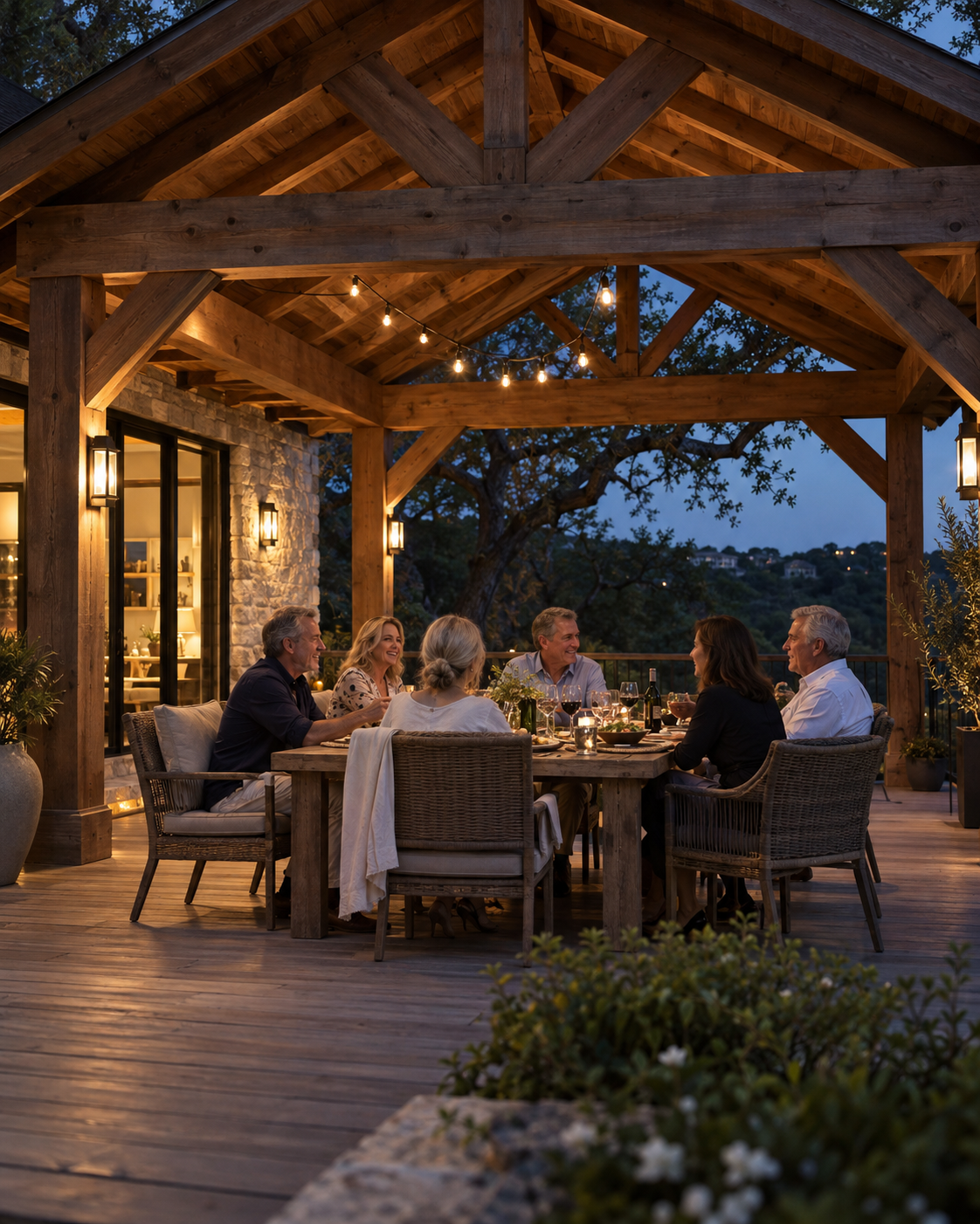 Friends gathered for dinner under a timber-framed covered patio at dusk