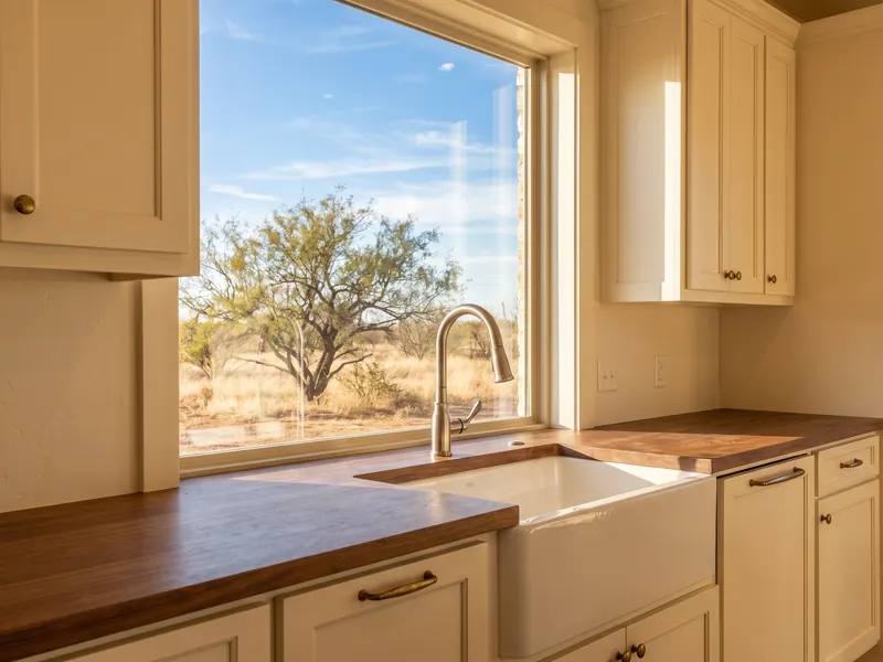 Kitchen sink window looking out to a West Texas backyard with a mesquite tree at midday