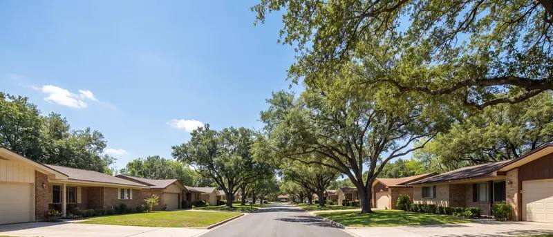 Wide Lubbock residential street with brick ranch homes under a big blue sky
