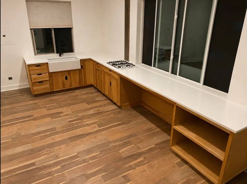 Rustic birch kitchen cabinets with white quartz countertops and wood-look tile floor