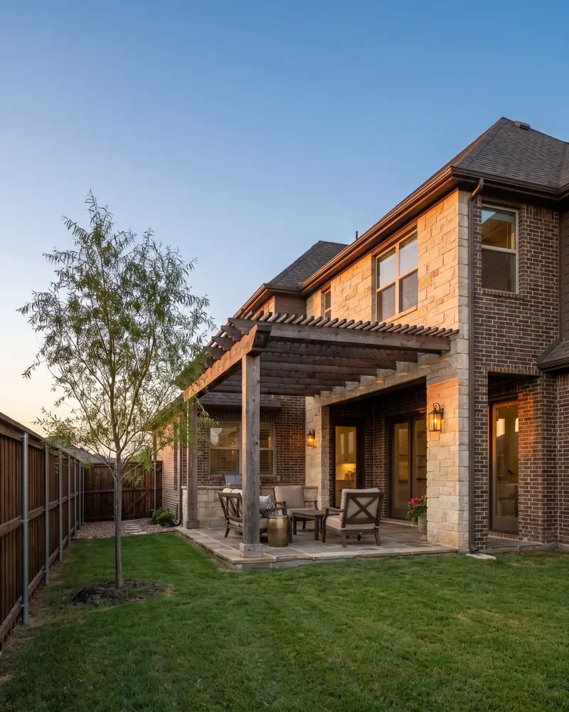 Stone and brick home in southwest Lubbock with a cedar pergola over the back patio at dusk