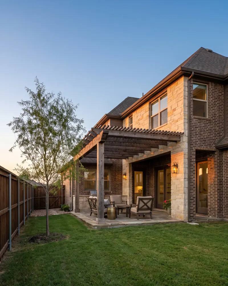Stone and brick home in southwest Lubbock with a cedar pergola over the back patio at dusk