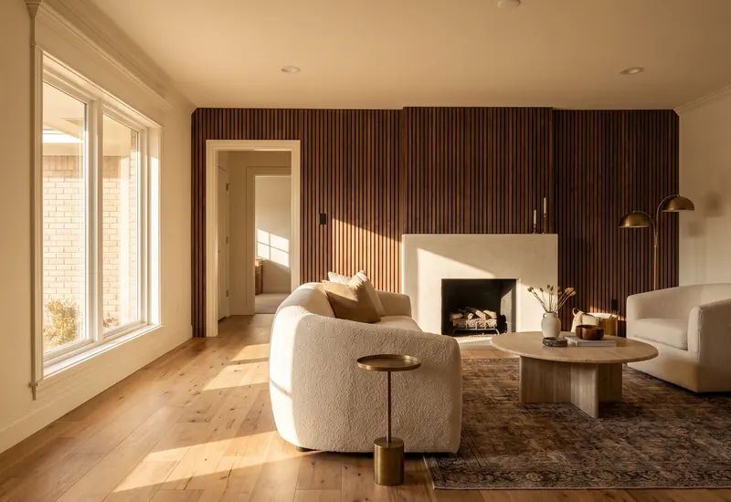 Living room with a walnut slat feature wall, plaster fireplace, and wide plank hickory floor
