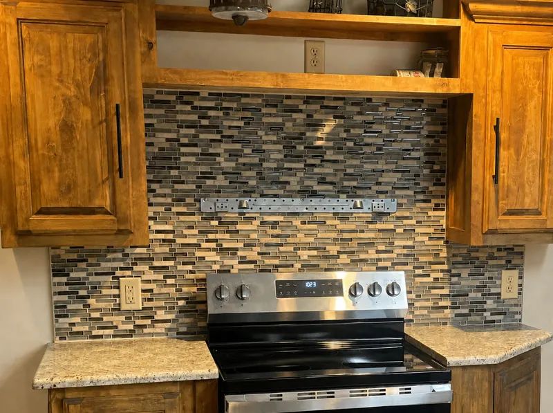 Kitchen with a glass and stone mosaic tile backsplash behind the range