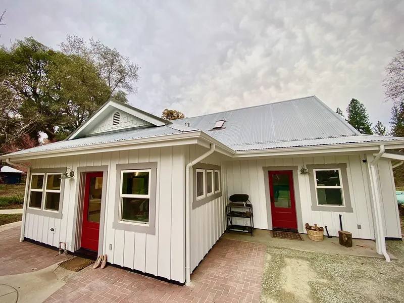Rear of a white farmhouse with new board and batten siding and red doors