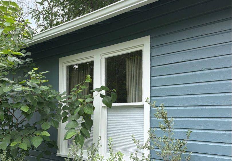Before and after photo of exterior siding around a window repainted by Hill Country Painting in Austin, TX