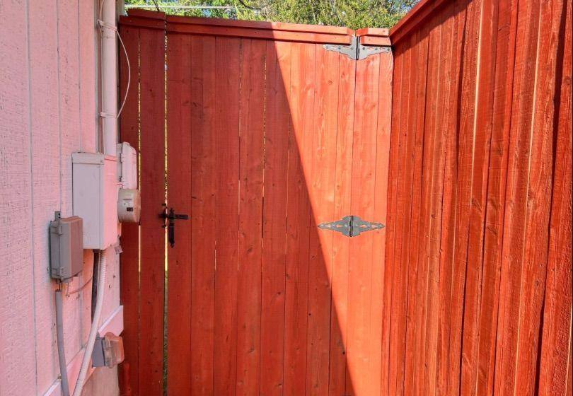 Before and after photo of a backyard fence stained by Hill Country Painting in Austin, TX