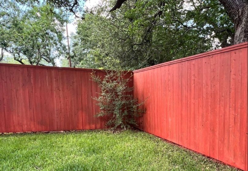 Before and after photo of a backyard fence line stained by Hill Country Painting in Austin, TX