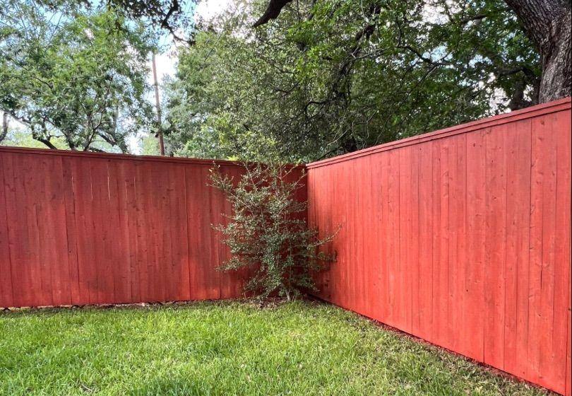 Before and after photo of a backyard fence line stained by Hill Country Painting in Austin, TX