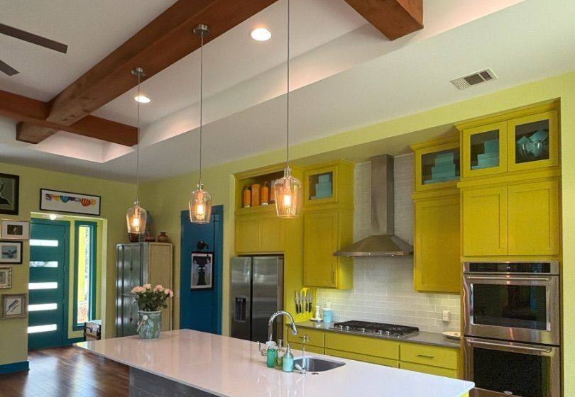 Before and after photo of a kitchen with yellow cabinets painted by Hill Country Painting in Austin, TX