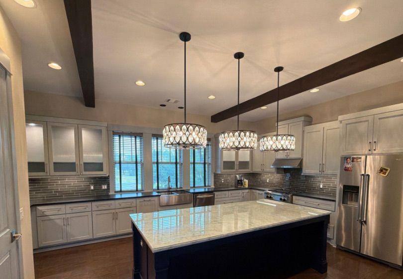 Before and after photo of kitchen cabinets repainted by Hill Country Painting in Spicewood, TX