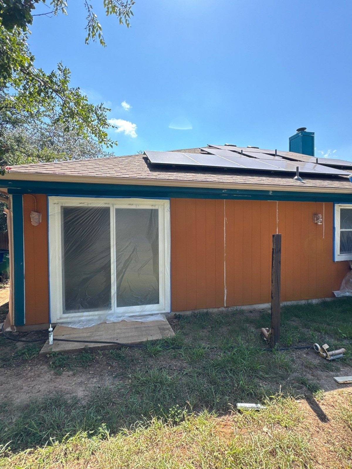 Back exterior of a home in Austin, TX with solar panels, ahead of siding and trim painting by Hill Country Painting