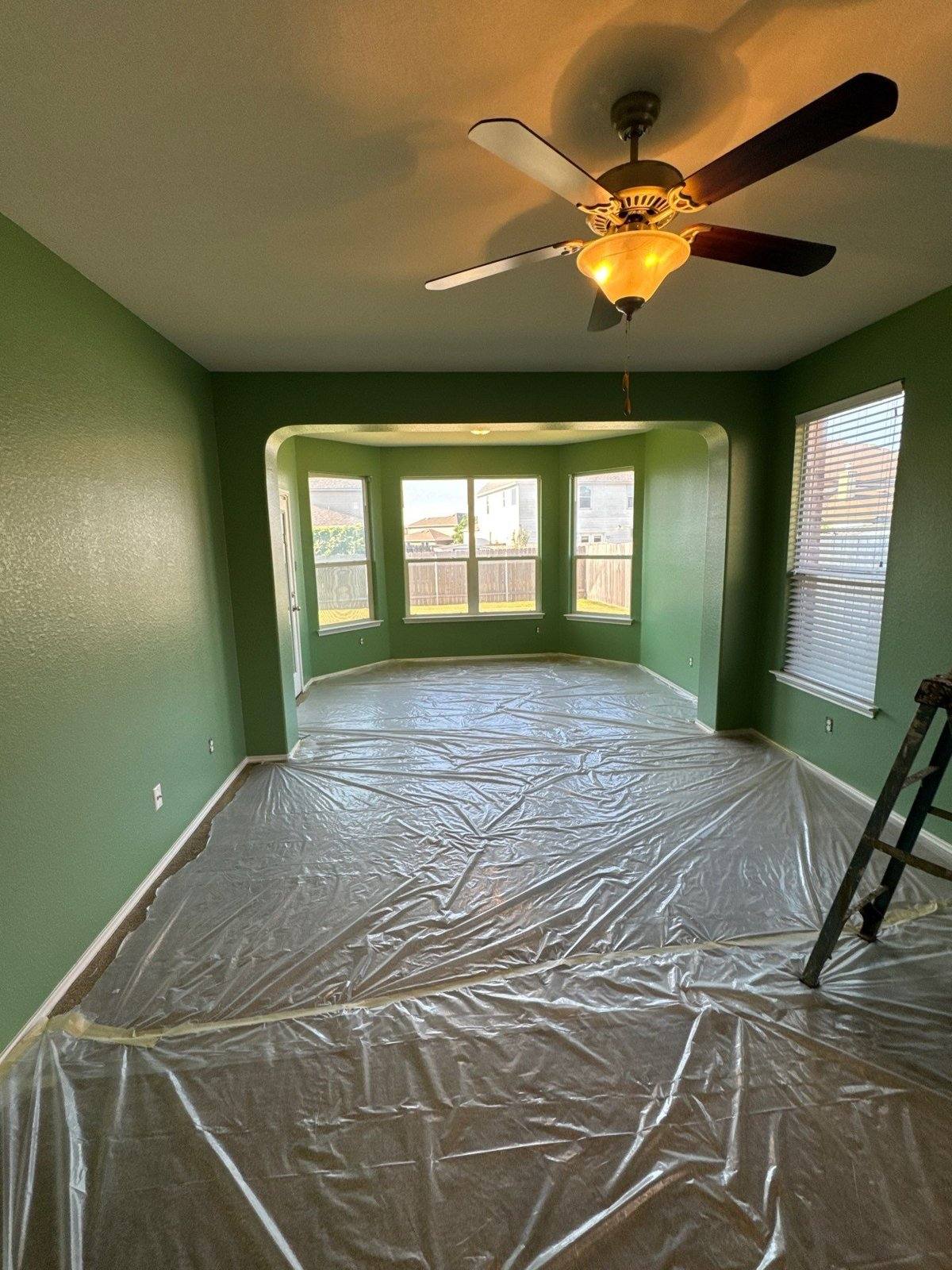 Living area with bay window in a Pflugerville, TX home, floors covered ahead of interior wall painting by Hill Country Painting