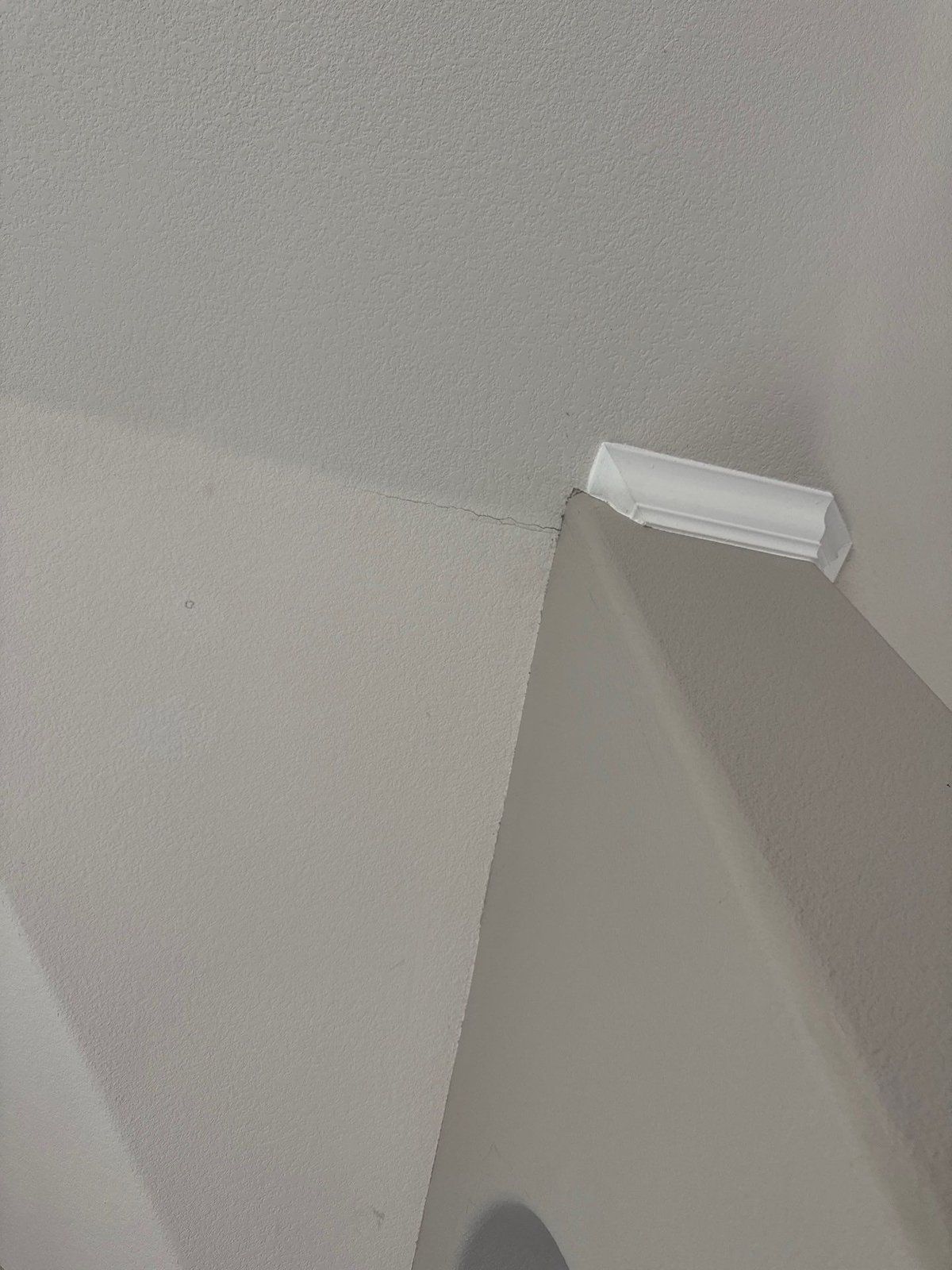 Settle crack at a ceiling corner with a crown molding sample, ahead of repair and repaint in Cedar Park, TX by Hill Country Painting