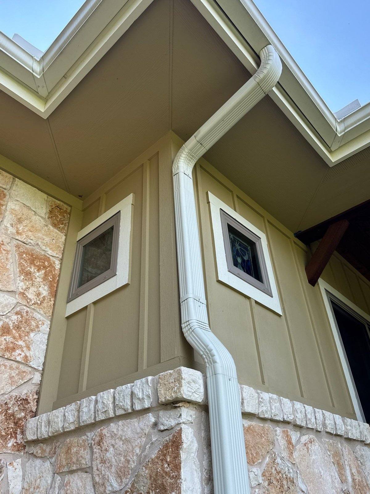 Siding corner with stone accent base ahead of an exterior repaint in Georgetown, TX by Hill Country Painting