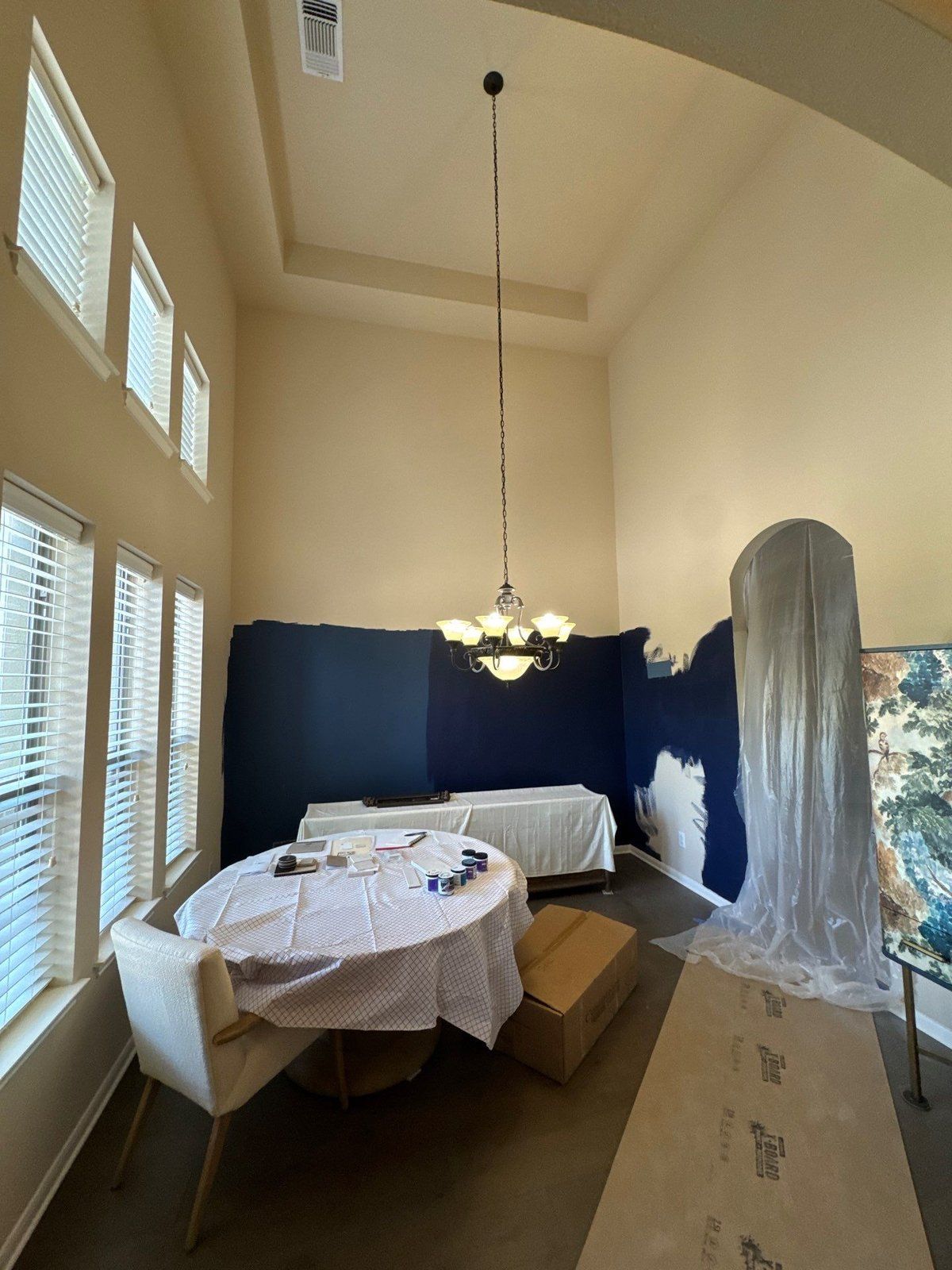 Two-story entryway mid-repaint with a navy accent wall in Austin, TX by Hill Country Painting