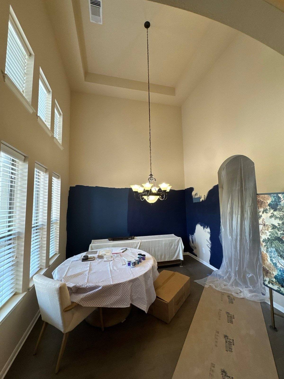 Two-story entryway mid-repaint with a navy accent wall in Austin, TX by Hill Country Painting