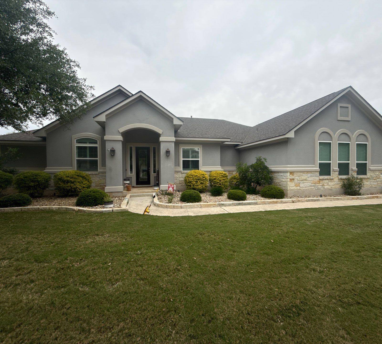 Front elevation of a stucco and stone home ahead of exterior painting in Leander, TX by Hill Country Painting