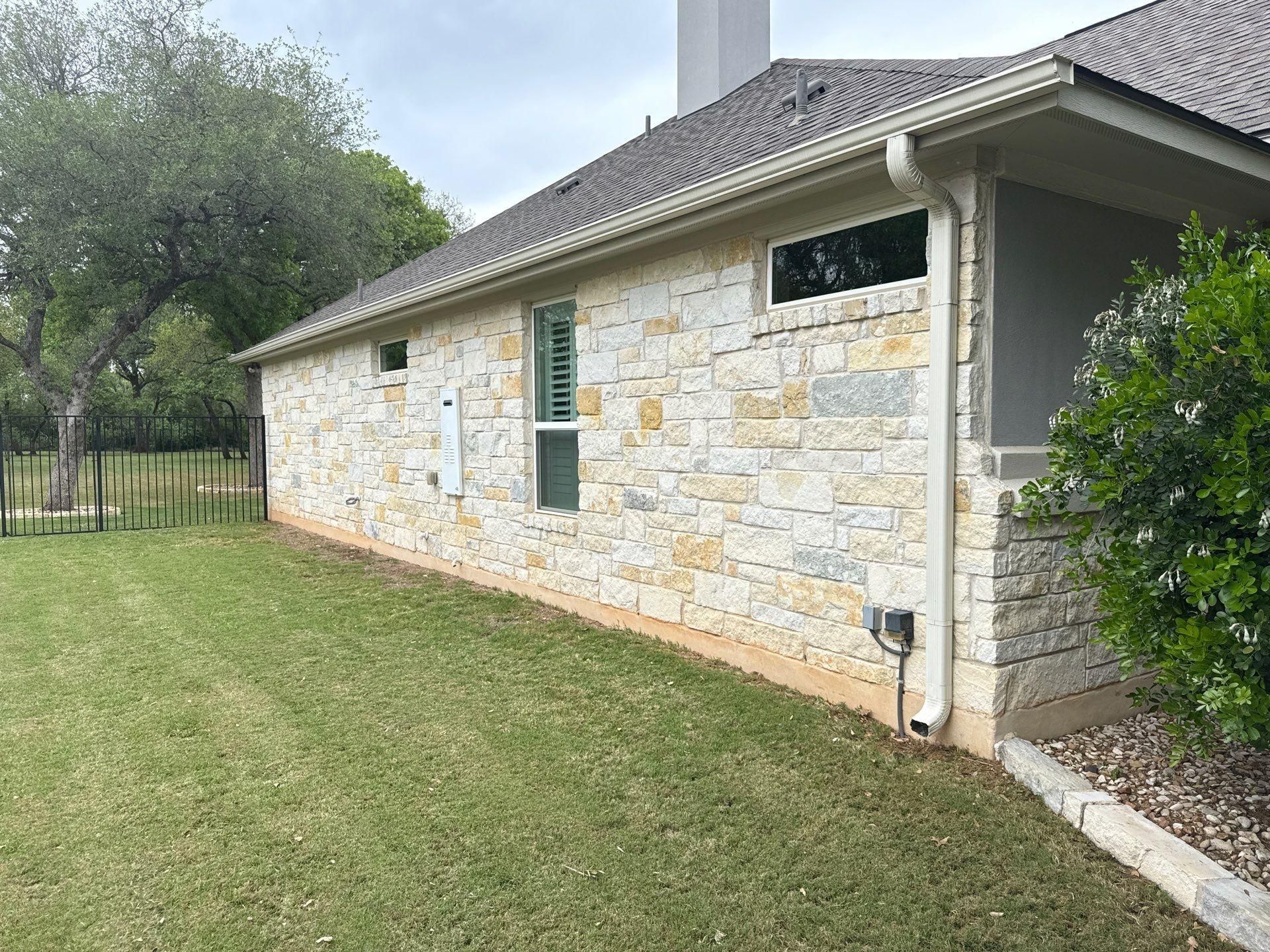 Side elevation with stone siding, gutters, and chimney ahead of exterior painting in Leander, TX by Hill Country Painting