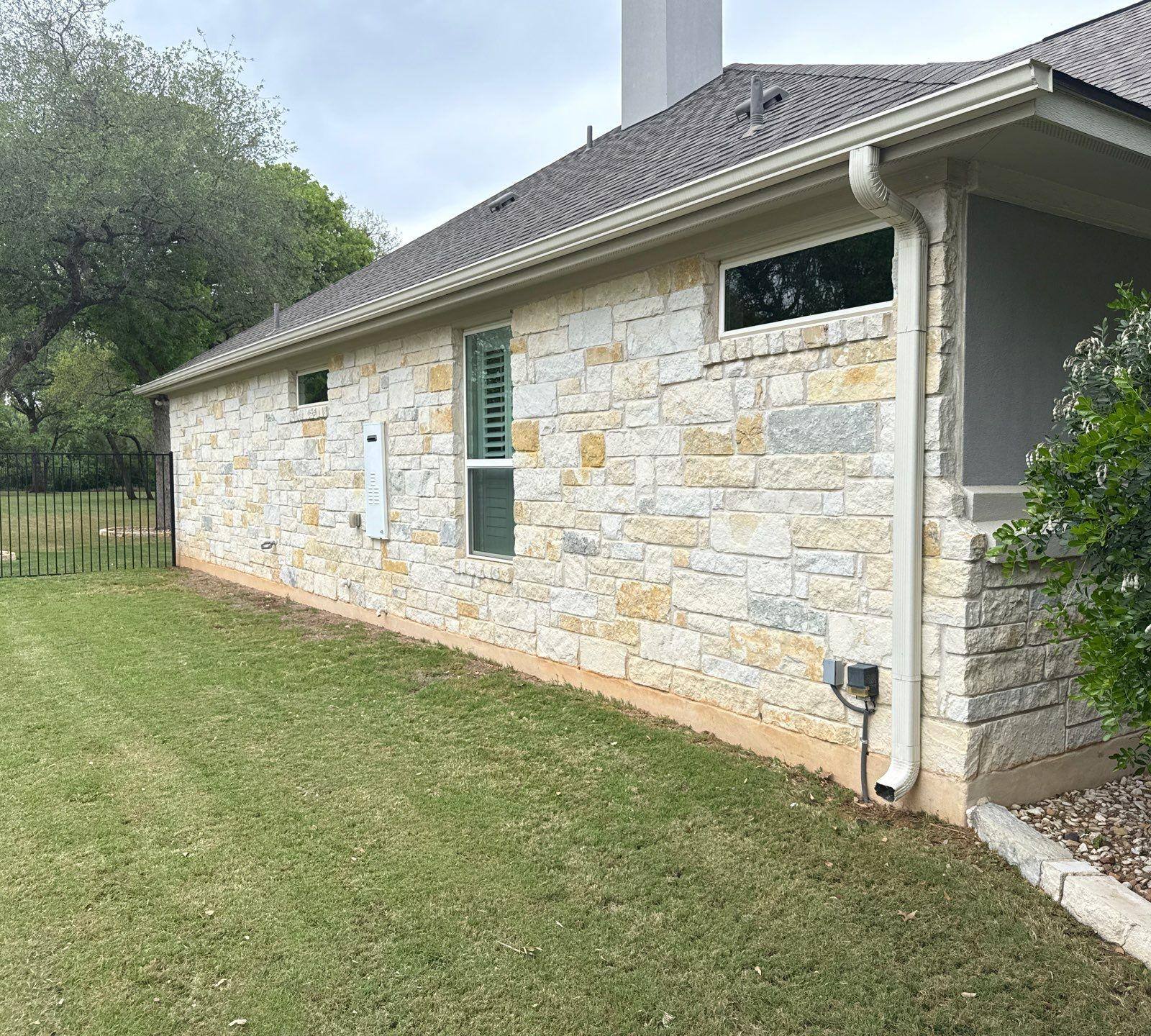 Side elevation with stone siding, gutters, and chimney ahead of exterior painting in Leander, TX by Hill Country Painting