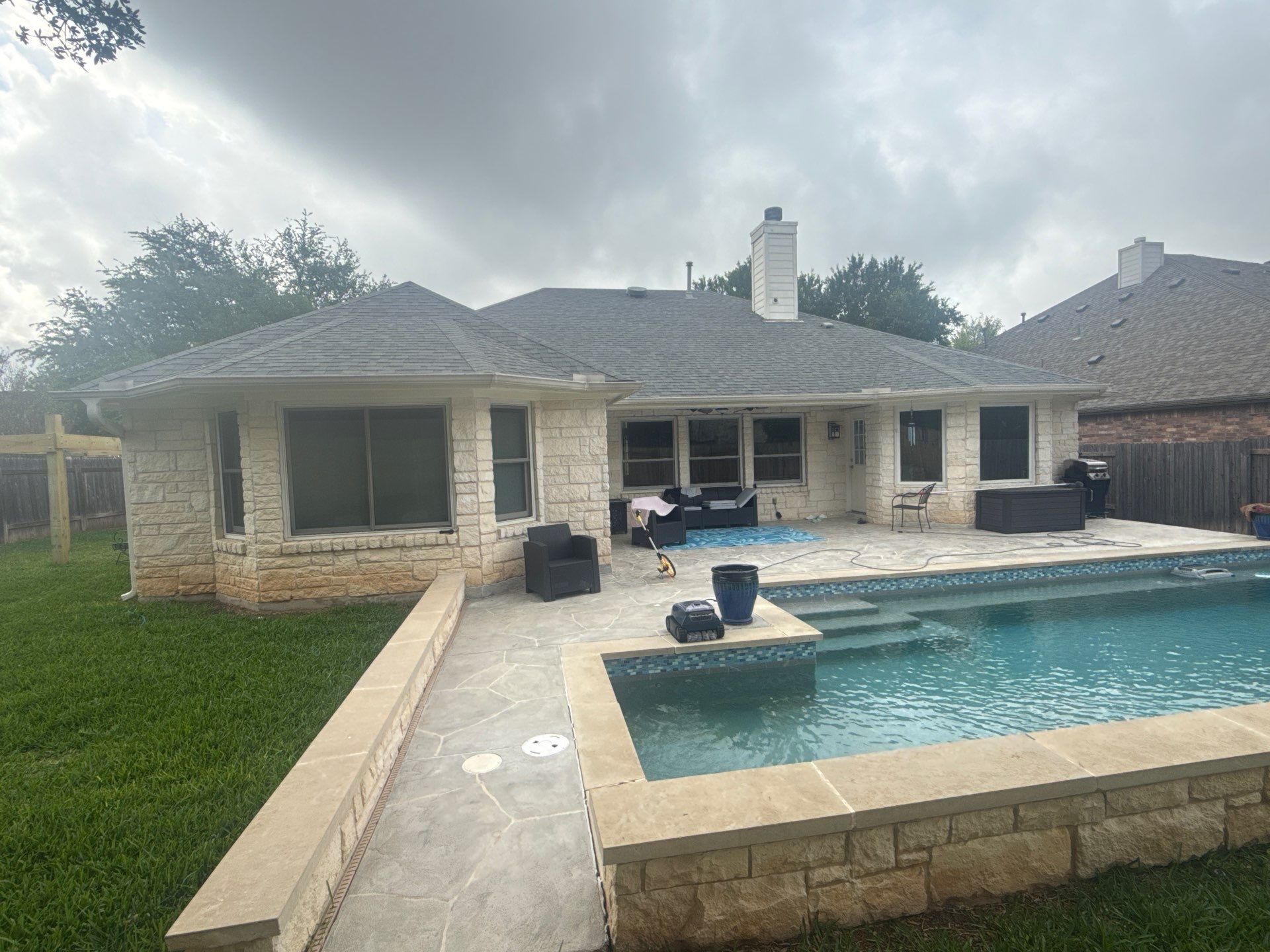 Back elevation of a stone home with pool ahead of exterior painting in Cedar Park, TX by Hill Country Painting