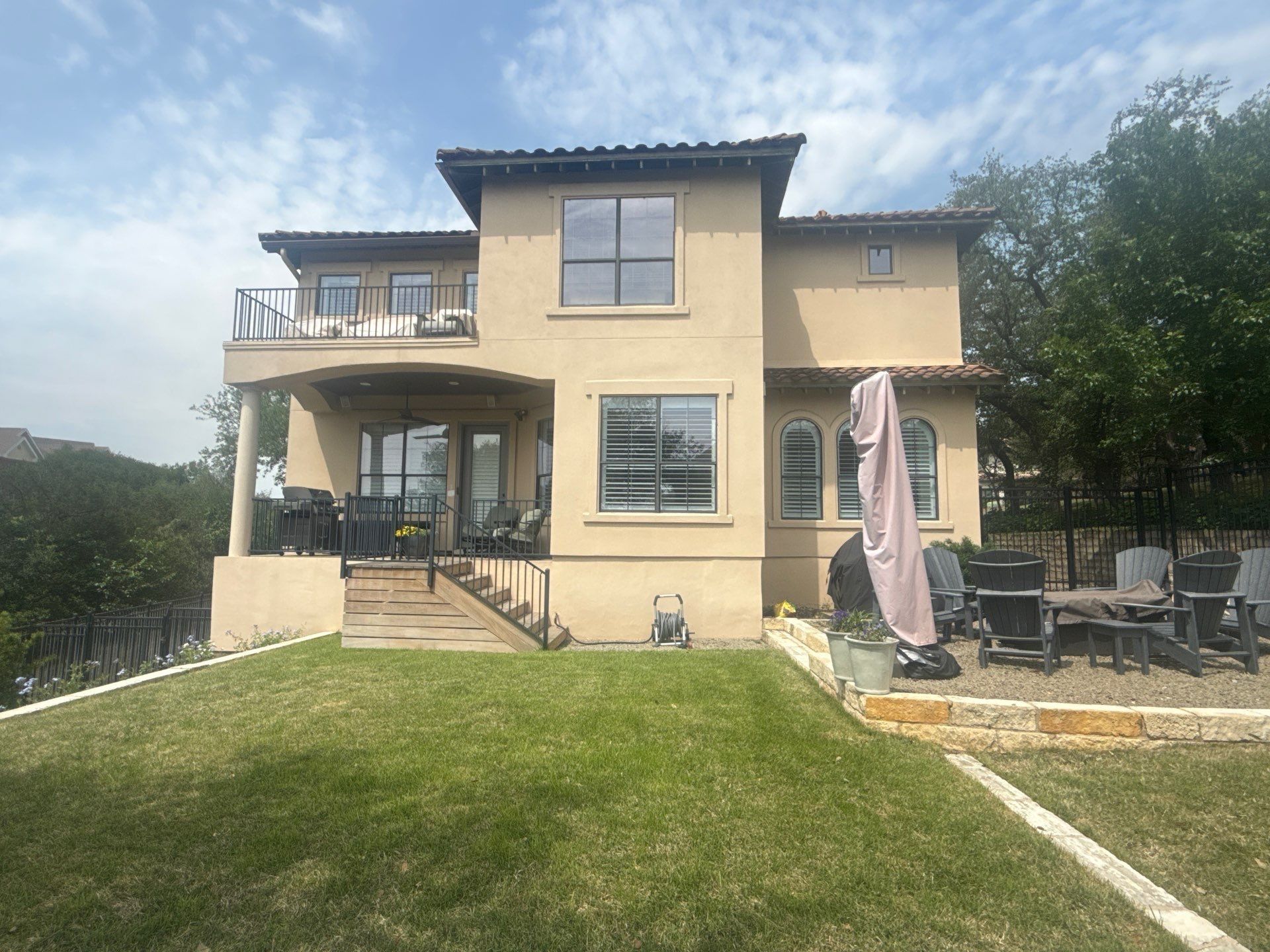 Back exterior of a two-story stucco home in Austin, TX ahead of exterior painting by Hill Country Painting