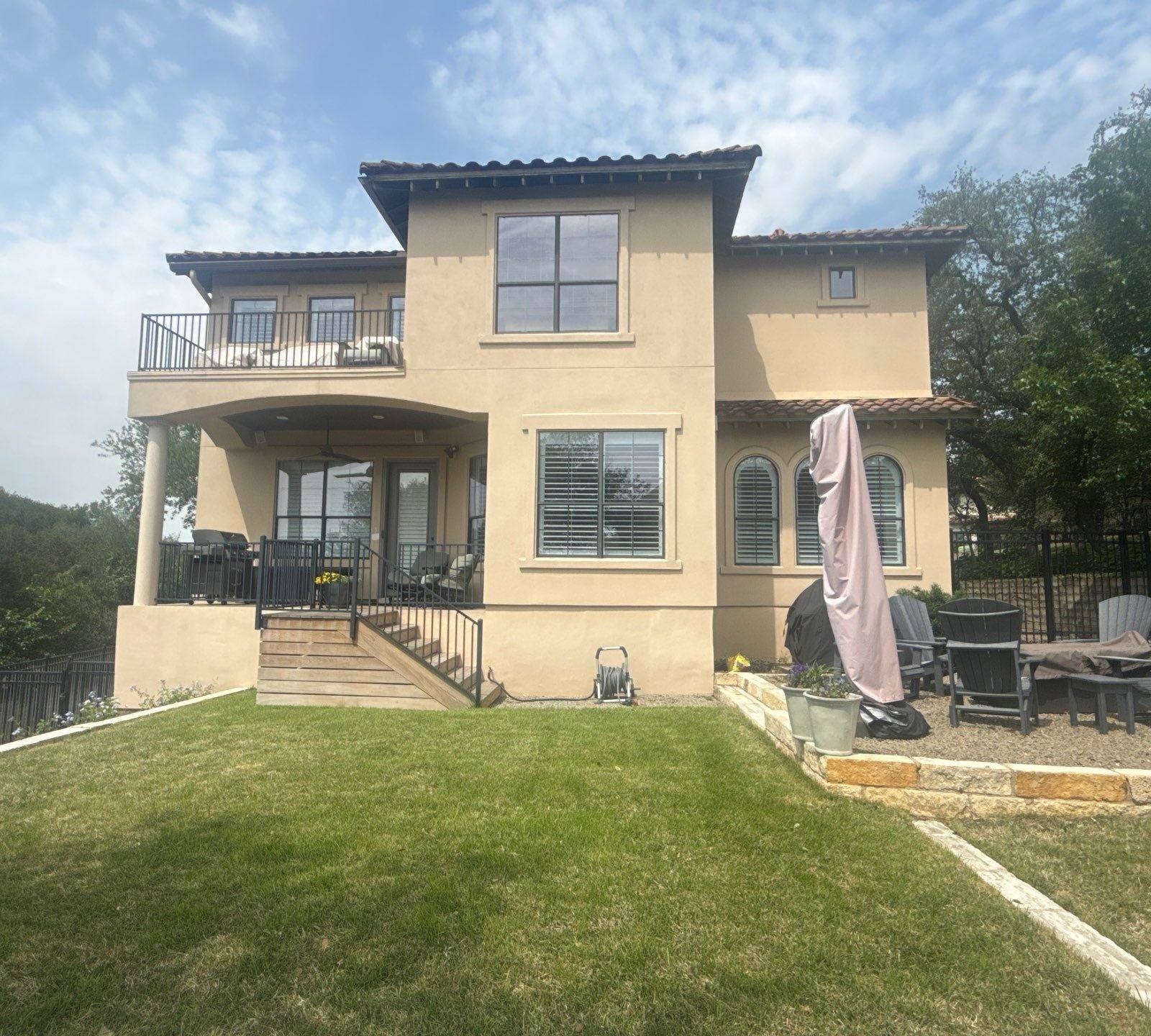 Back exterior of a two-story stucco home in Austin, TX ahead of exterior painting by Hill Country Painting