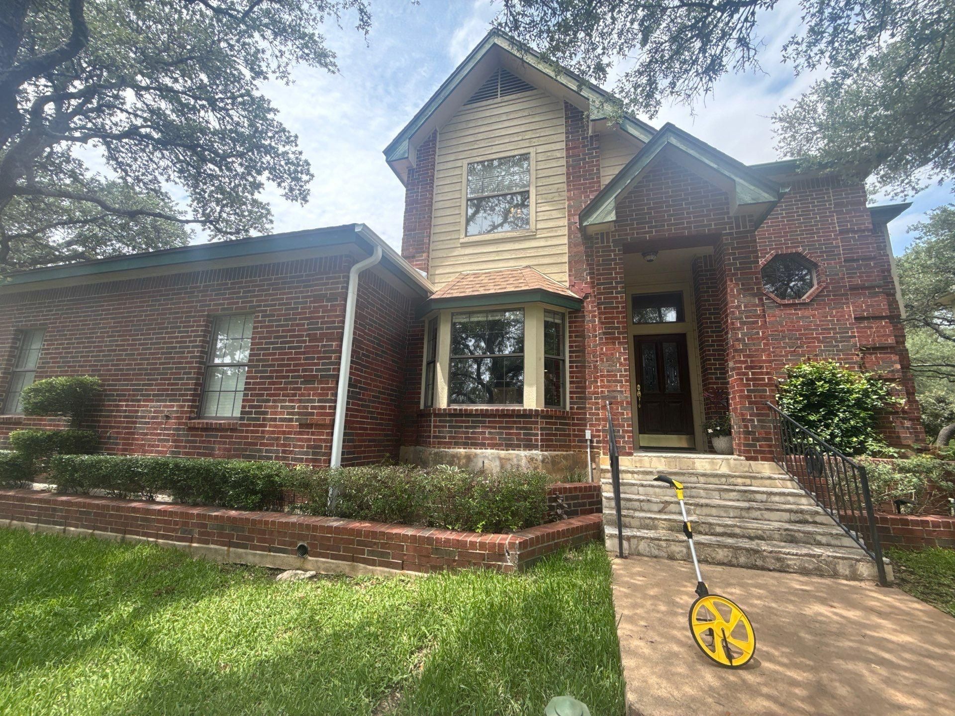 Two-story brick home with front entry and bay window in Lakeway, TX ahead of exterior painting by Hill Country Painting