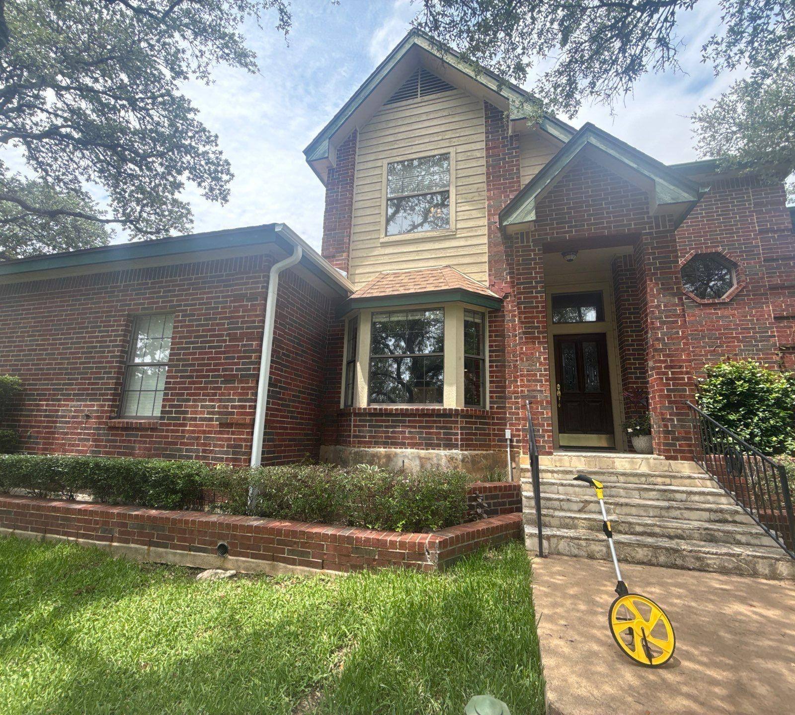 Two-story brick home with front entry and bay window in Lakeway, TX ahead of exterior painting by Hill Country Painting