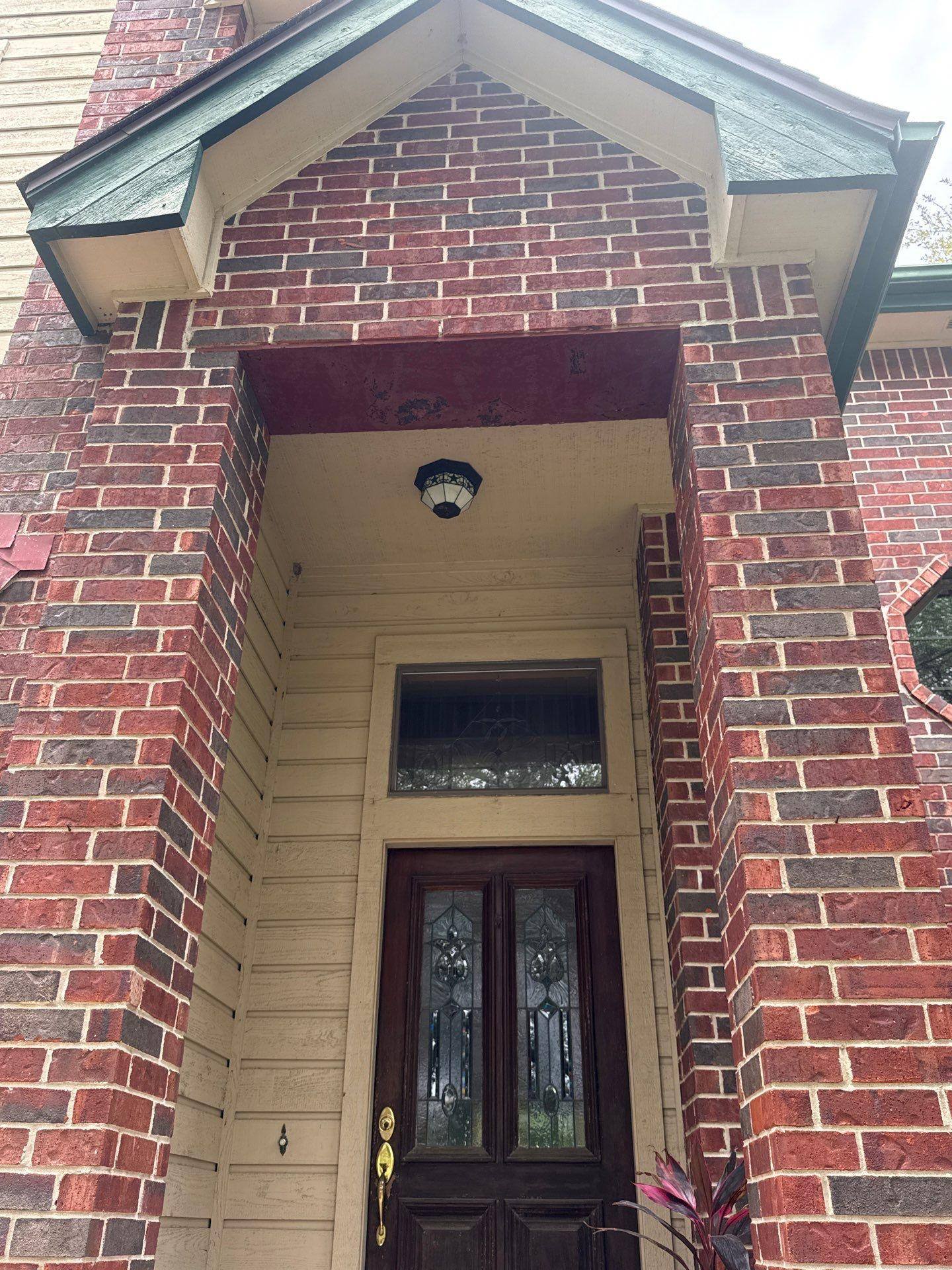 Glass-panel front entry door with brick surround on a home in Lakeway, TX ahead of exterior painting by Hill Country Painting