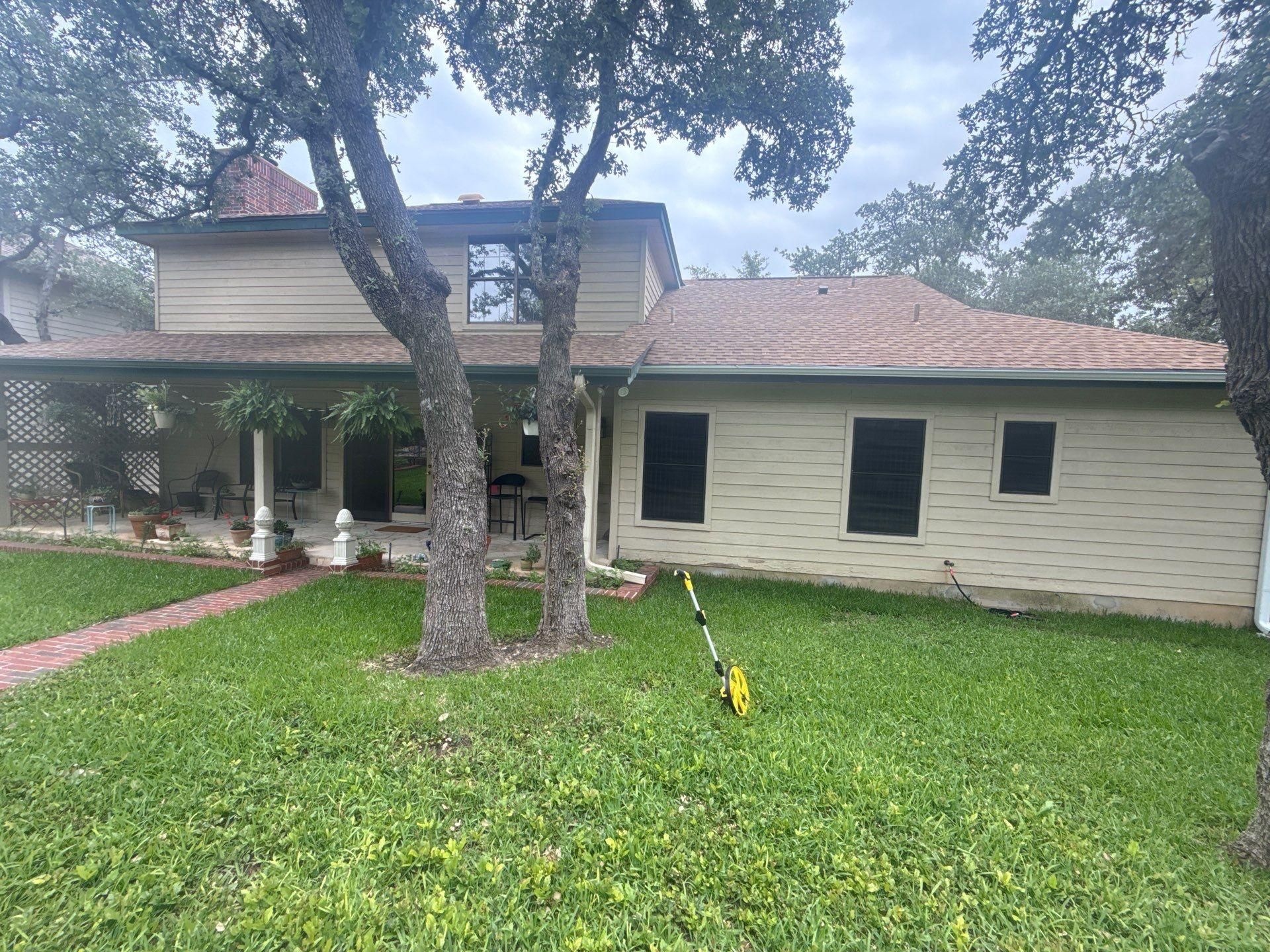Back exterior of a brick home with covered porch in Lakeway, TX ahead of exterior painting by Hill Country Painting