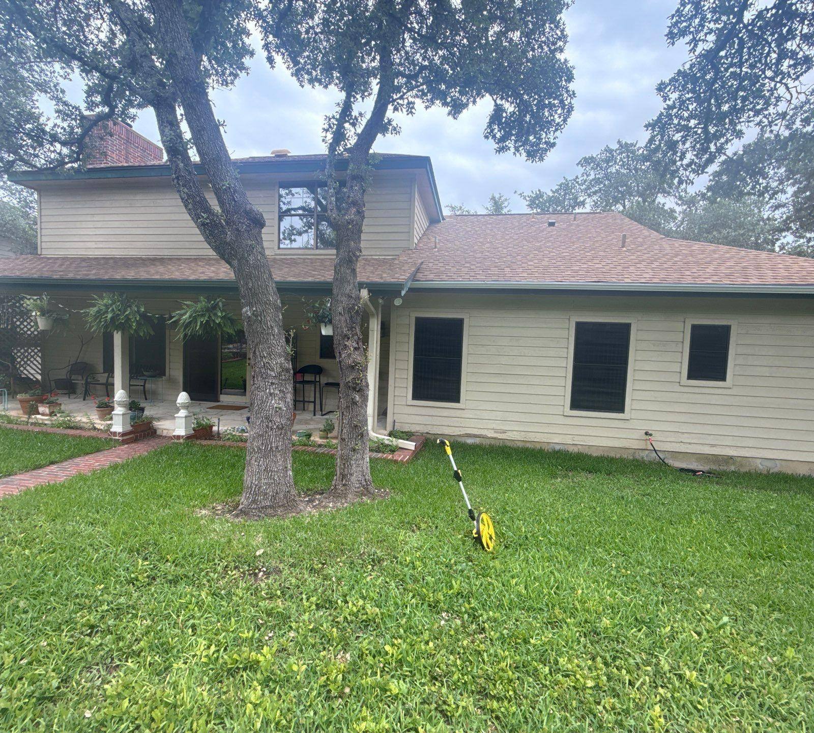 Back exterior of a brick home with covered porch in Lakeway, TX ahead of exterior painting by Hill Country Painting