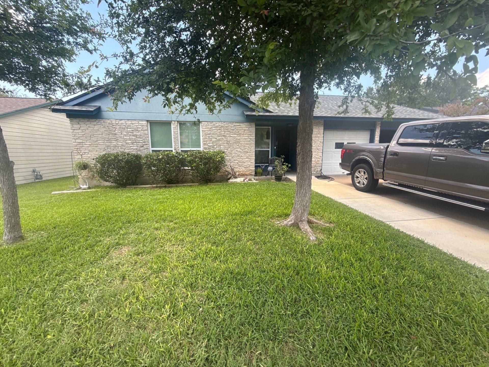 Single-story stone and siding home with attached garage in Austin, TX ahead of exterior painting by Hill Country Painting
