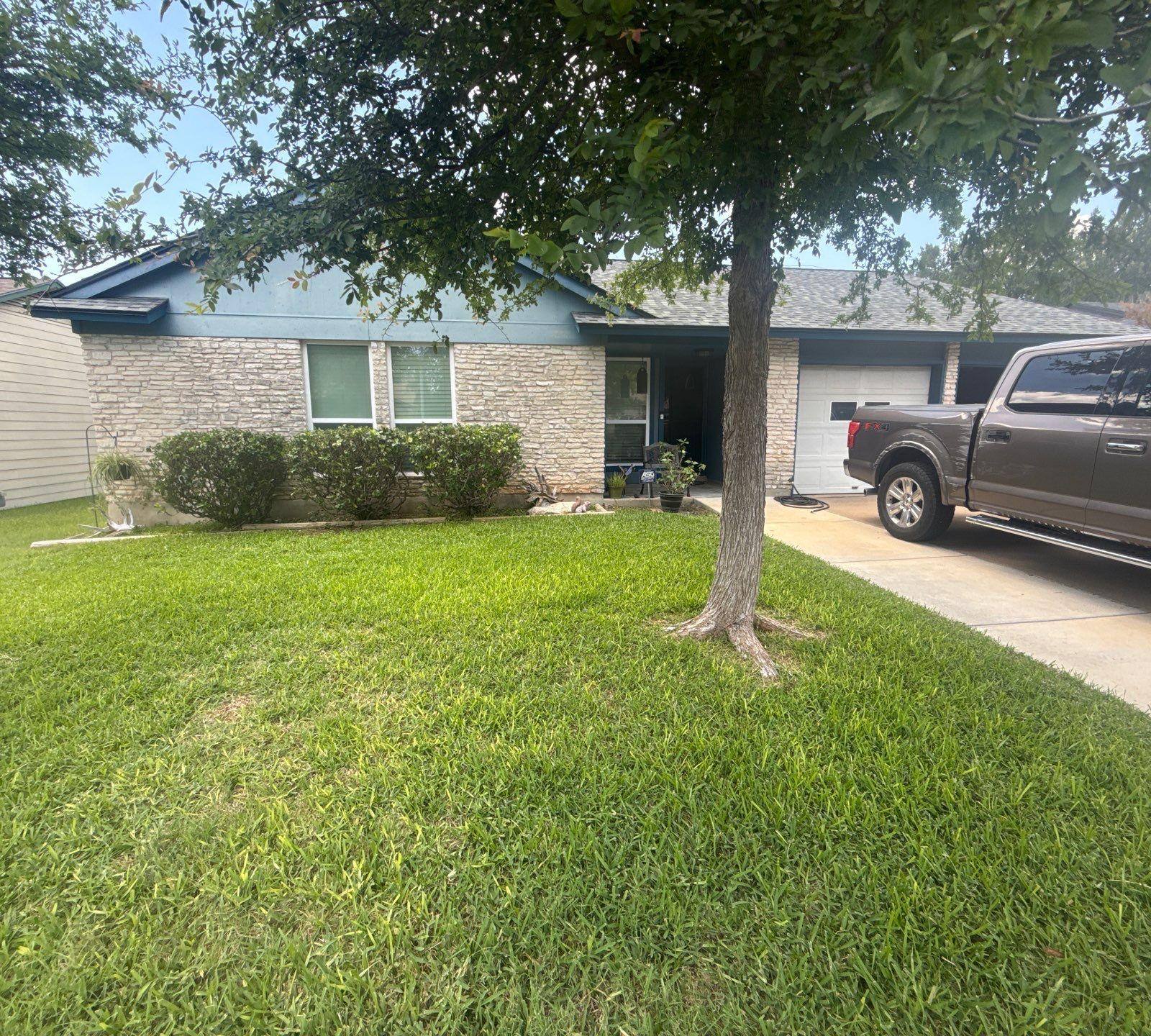 Single-story stone and siding home with attached garage in Austin, TX ahead of exterior painting by Hill Country Painting