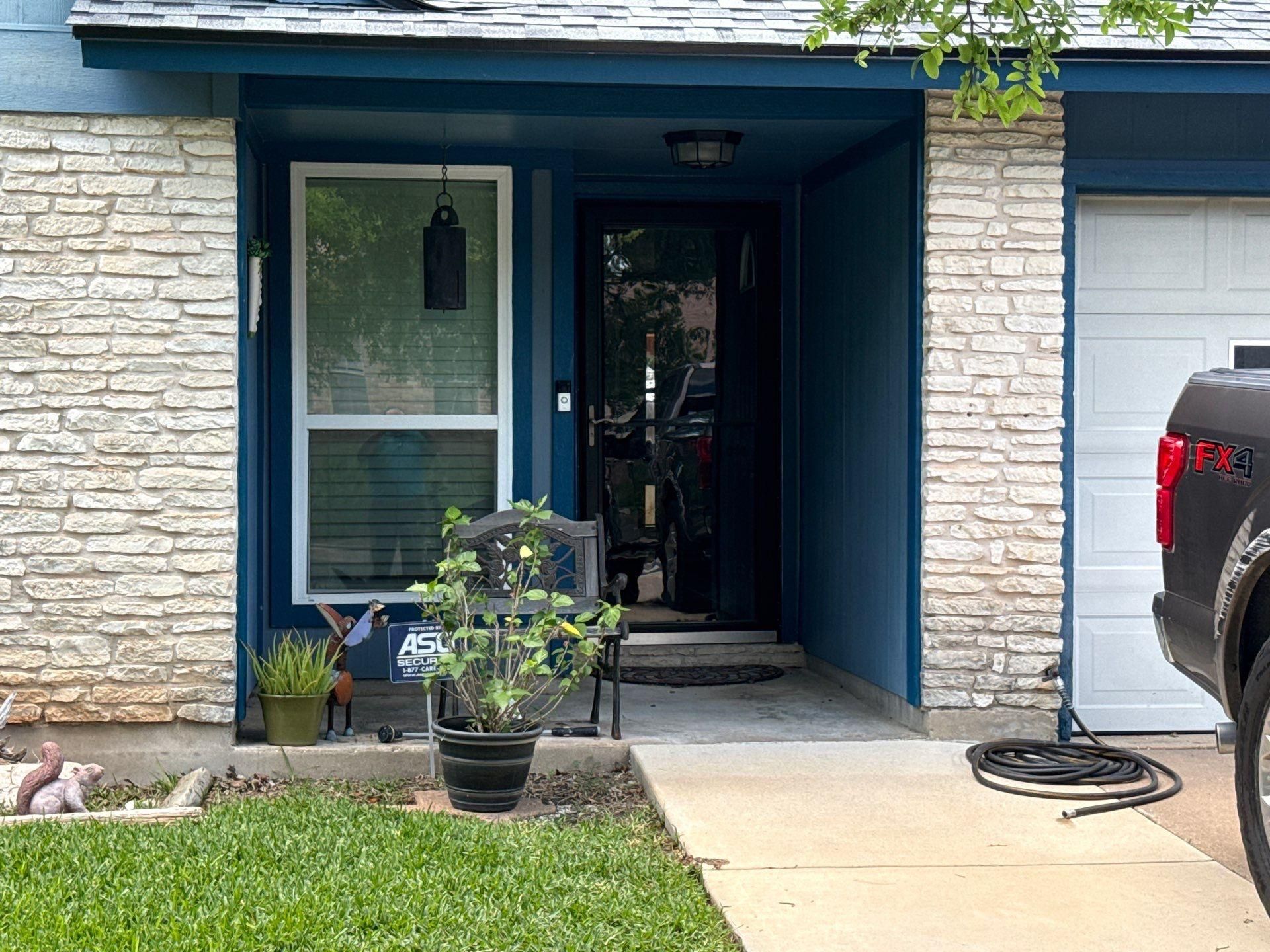 Covered front entry with stone surround on a home in Austin, TX ahead of exterior painting by Hill Country Painting