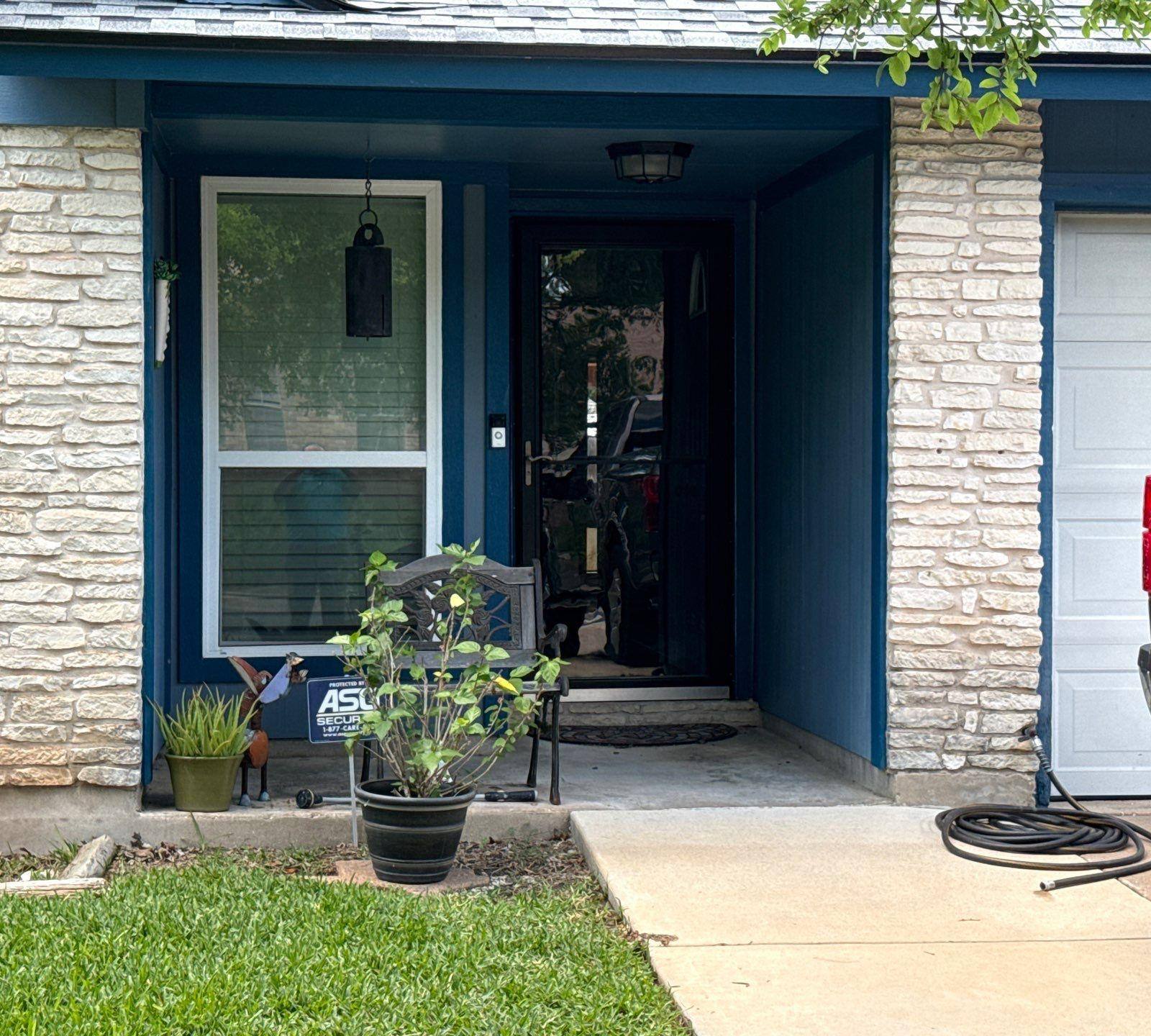 Covered front entry with stone surround on a home in Austin, TX ahead of exterior painting by Hill Country Painting