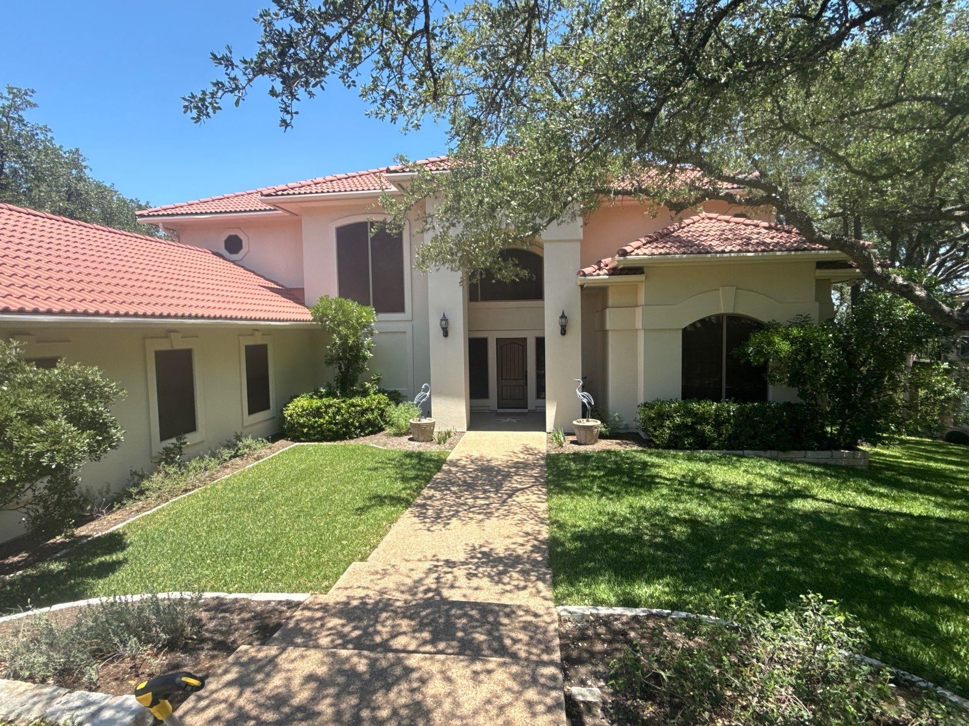Two-story stucco home with tile roof on Golf Crest Ln in Lakeway, TX ahead of exterior painting by Hill Country Painting