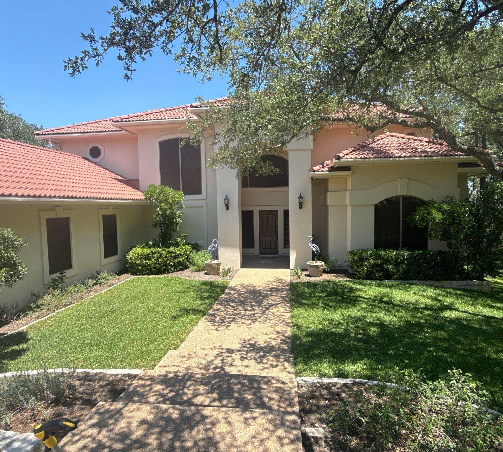 Two-story stucco home with tile roof on Golf Crest Ln in Lakeway, TX ahead of exterior painting by Hill Country Painting