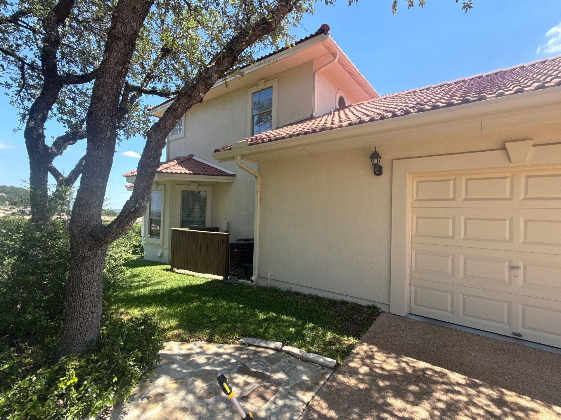Side exterior and garage of a two-story stucco home in Lakeway, TX ahead of exterior painting by Hill Country Painting