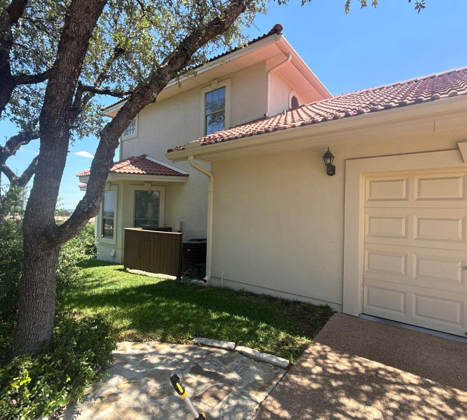 Side exterior and garage of a two-story stucco home in Lakeway, TX ahead of exterior painting by Hill Country Painting