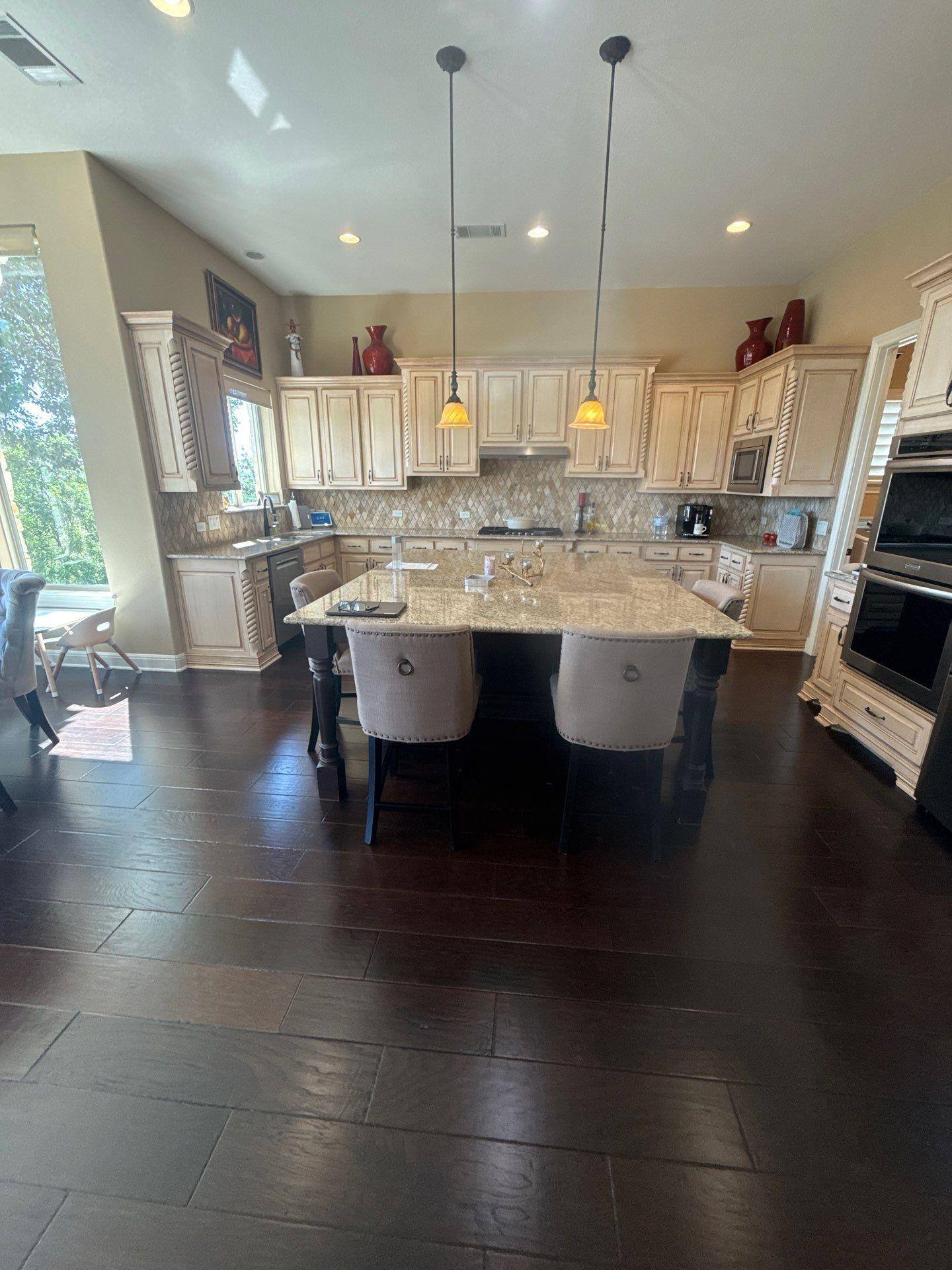 Kitchen with island and cream cabinetry in a home on Martinique Pass in Austin, TX ahead of interior painting by Hill Country Painting