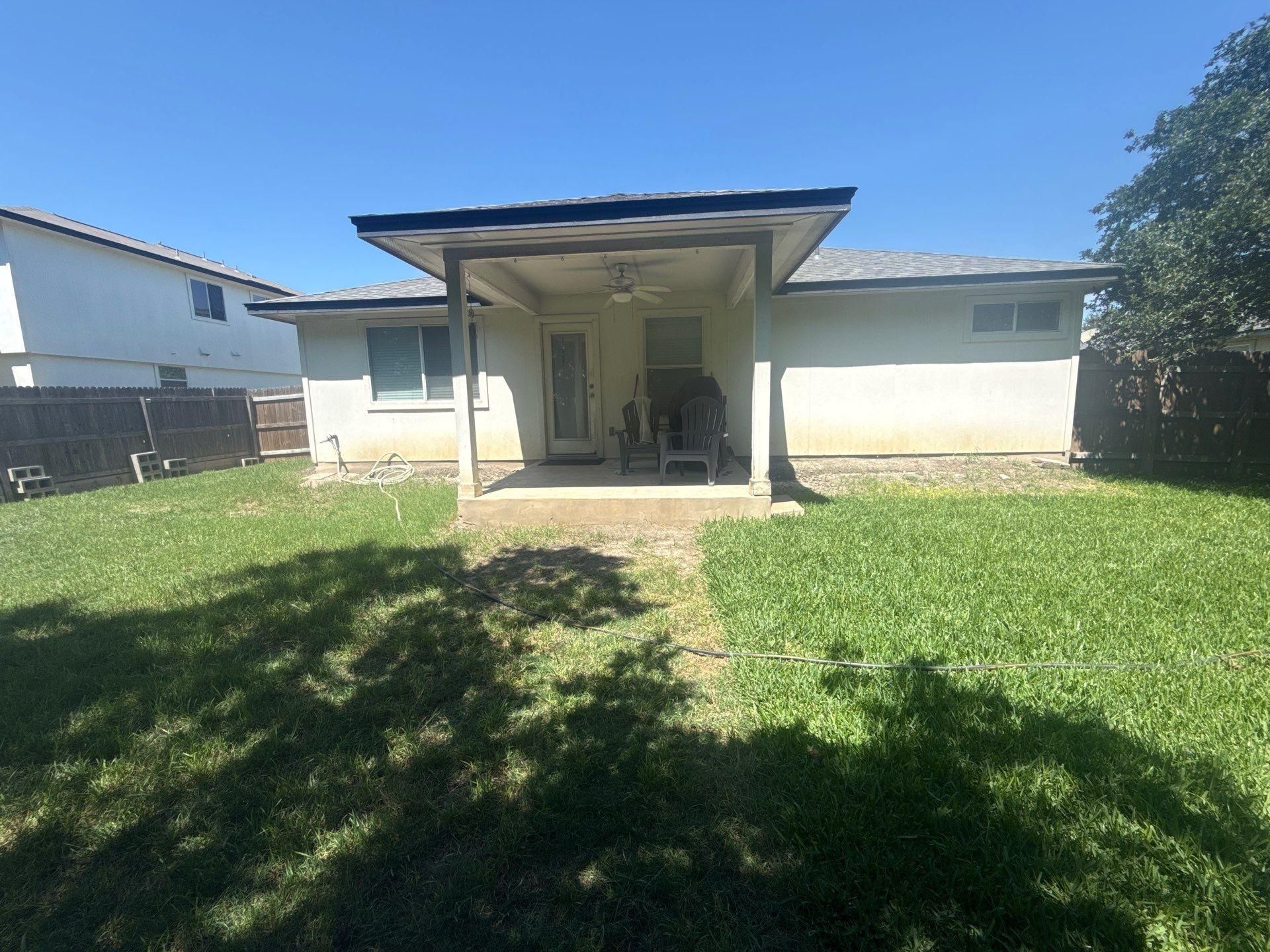 Back exterior and covered patio of a home on Delby St in Hutto, TX ahead of exterior painting by Hill Country Painting