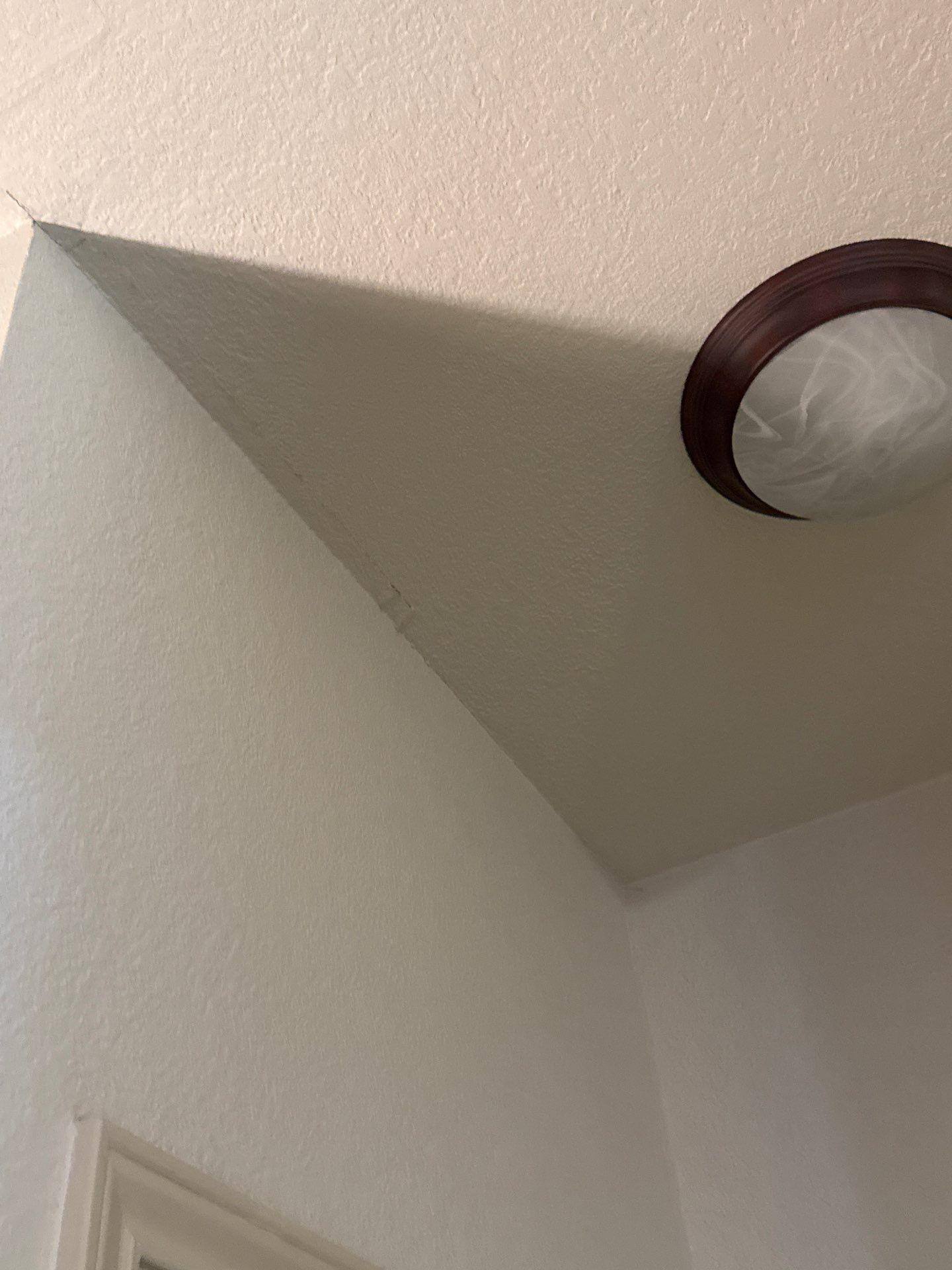 Vaulted ceiling corner near a light fixture ahead of interior painting by Hill Country Painting in Round Rock, TX