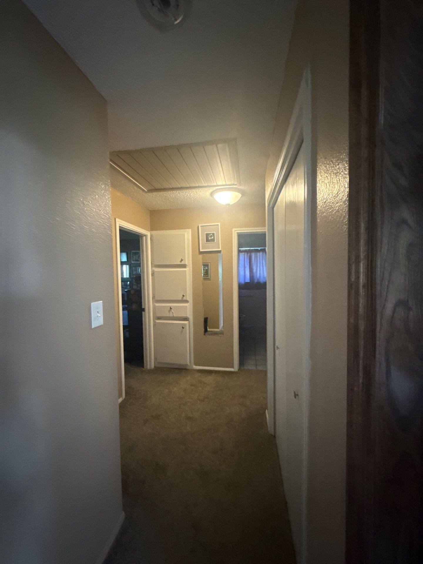 Hallway with built-in cabinet and shelving in a home on Granada Hills Dr in Austin, TX prepared for painting by Hill Country Painting