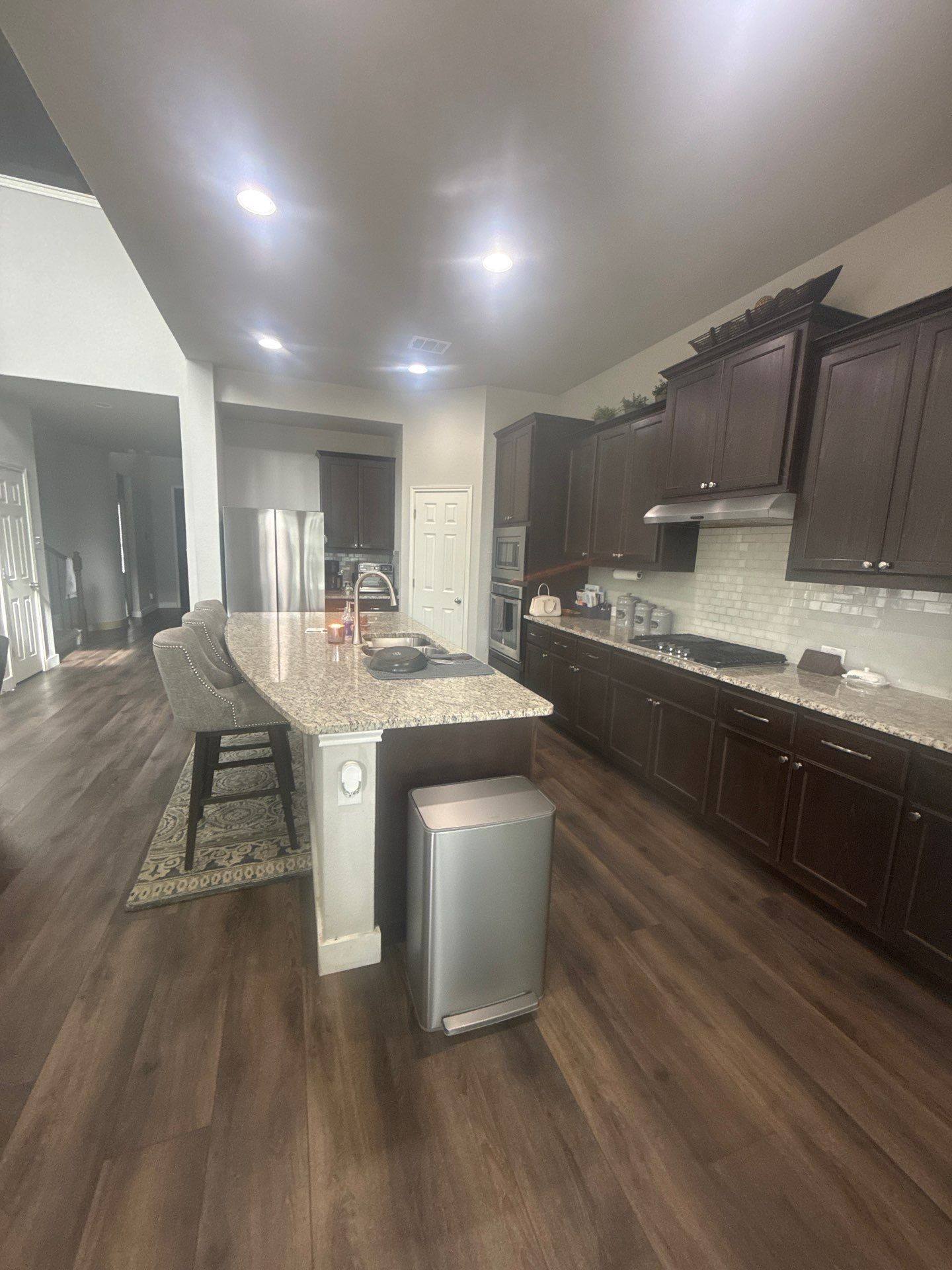 Kitchen with wood cabinets and granite countertops in a home on Kite Wing Ter in Pflugerville, TX prepared for painting by Hill Country Painting