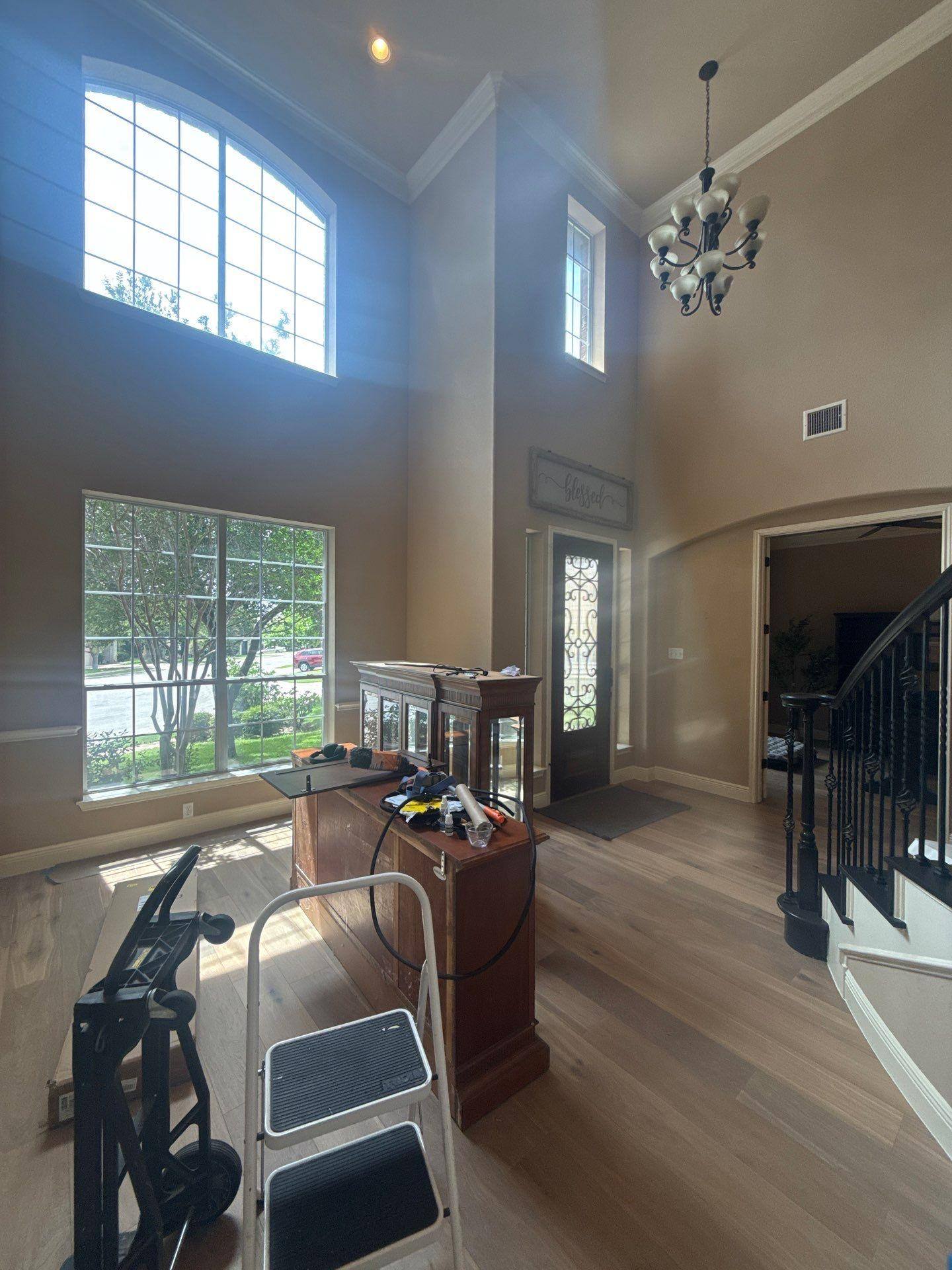 Two-story entryway with vaulted ceiling and staircase in a home on Rhondstat Run in Cedar Park, TX prepared for painting by Hill Country Painting