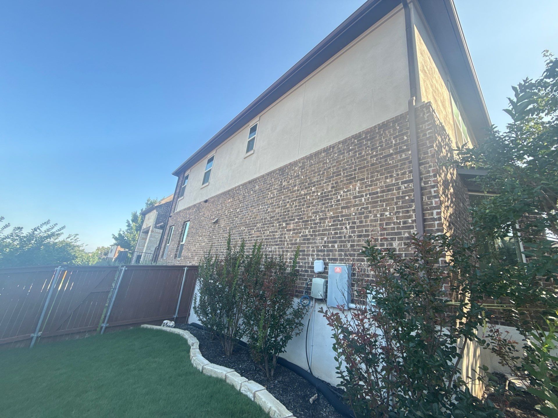 Side elevation with brick and stucco siding at a home on Borho Ranch St in Leander, TX prepared for a painting estimate by Hill Country Painting