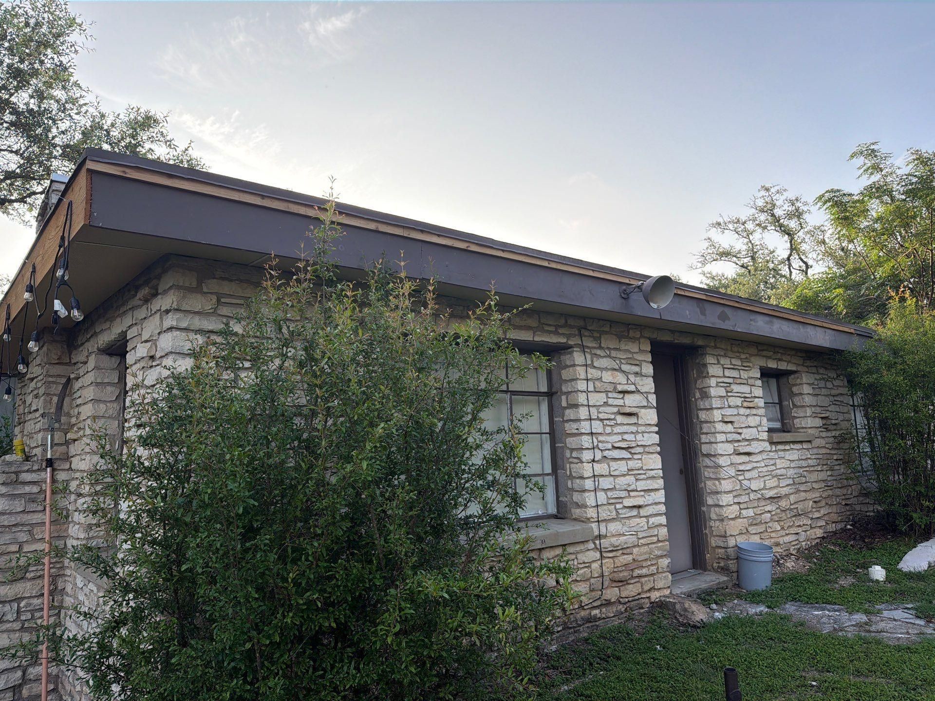 Side exterior stone detail of a home on St Stephens Dr in Austin, TX during an exterior painting project by Hill Country Painting