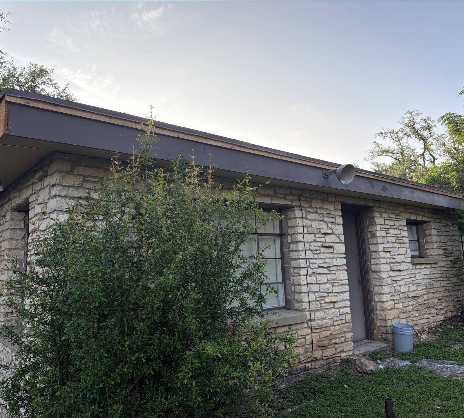 Side exterior stone detail of a home on St Stephens Dr in Austin, TX during an exterior painting project by Hill Country Painting