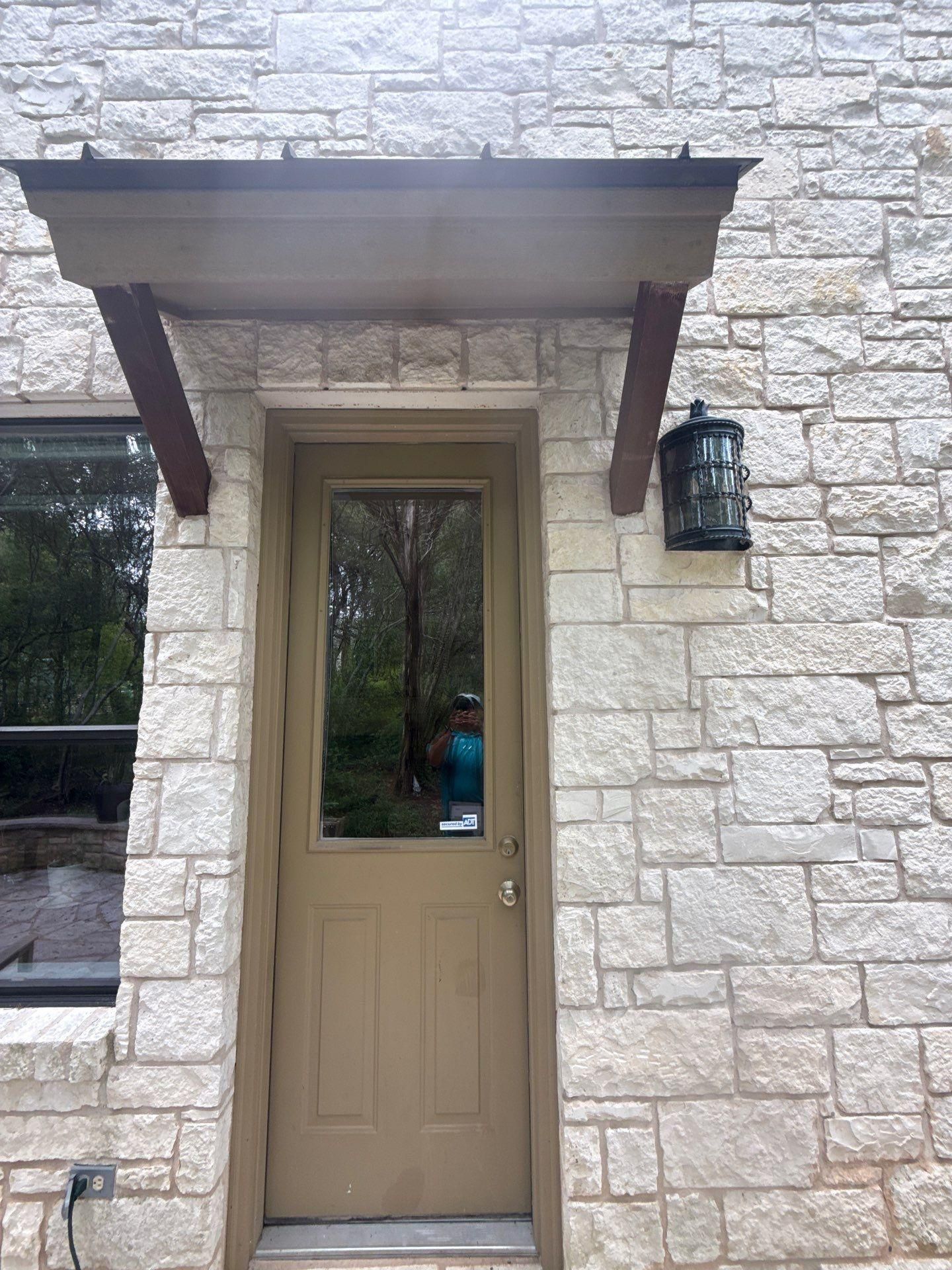 Arched stone entry door of a home on Gregory Pl in Austin, TX prepared for an exterior painting estimate by Hill Country Painting